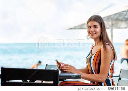 Portrait of a smiling woman sits in a cafe and uses a mobile phone. Concept of communication and business 89611466