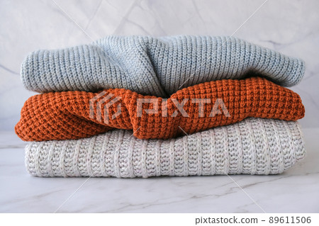 Stack of cozy knitted warm sweater. Sweaters in retro Style. Orange and blue colors. Cozy hygge concept Copy space 89611506