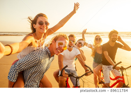 young cheerful friends self photographing on smartphone camera on the beach at sunset sunlight summer vacation 89611784