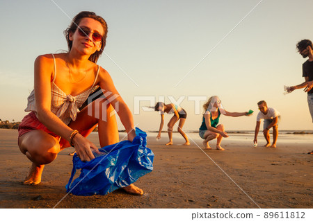 focus on cheerful girl cleaning the sandy beach from garbage with her friends on background volunteer team on eco-friendly movement in Goa India 89611812