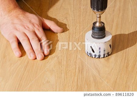 Worker with milling cutter in action at the workshop. Carpenter making holes in the wood board. DIY Worker with milling cutter in action at the workshop. Carpenter making holes in the wood board. DIY 89611820