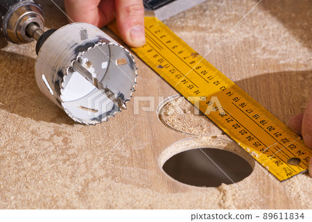 Worker with milling cutter in action at the workshop. Carpenter making holes in the wood board. DIY Worker with milling cutter in action at the workshop. Carpenter making holes in the wood board. DIY 89611834
