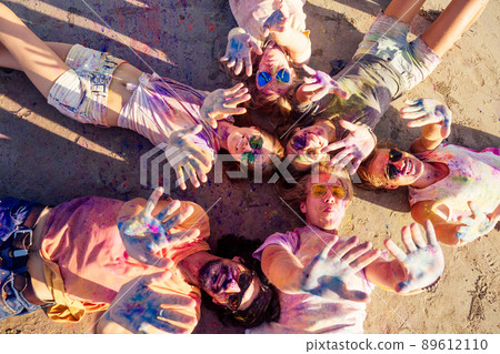 mixed race friends having fun with colors on seaside outdoors in Goa India 89612110