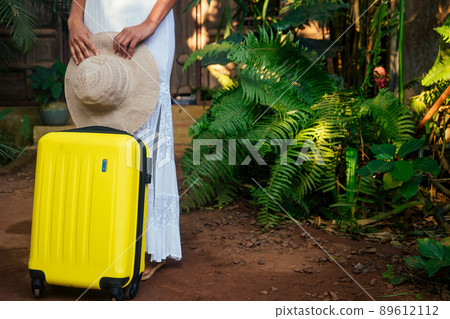 afro american tourist woman in white cotton lace long dress and straw eco hat going to hotel in tropics 89612112