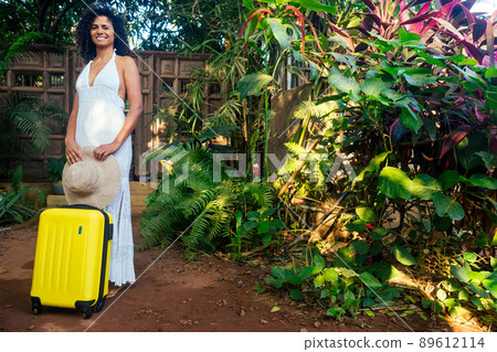 afro american tourist woman in white cotton lace long dress and straw eco hat going to hotel in tropics 89612114