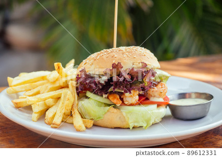 prawns burger and french fry on table tropical sea ,palms tree and beach background prawns burger and french fry on table tropical sea ,palms tree and beach background 89612331