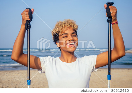 happy hispanic brazilian woman working out on beach . she wears white cotton t-shirt breathable clothes 89612410