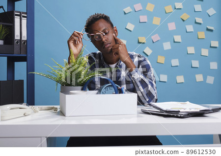 African american young adult left unemployed because of company unsuccessful financial recovery plan. Depressed and upset office worker gathering personal belongings because of job dismissal. African american young adult left unemployed because of company unsuccessful financial recovery plan. Depressed and upset office worker gathering personal belongings because of job dismissal. 89612530