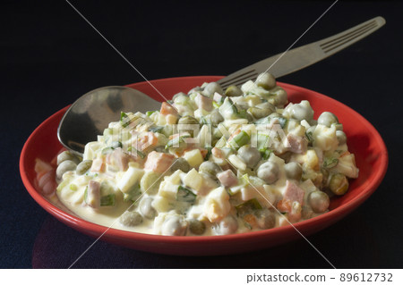 Olivier salad in a red plate on the table 89612732