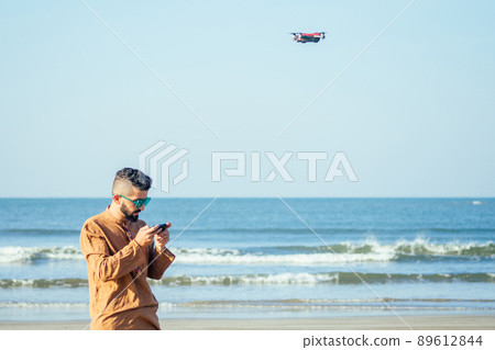 arabian man testing a drone photo and video shooting on quadrocopter over the sea in Goa beach 89612844