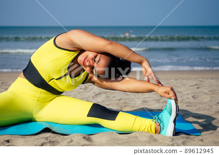 young indian woman practice asanas on blue yogic mat on goa beach . she wearing stylish yellow leggings and fitness top bra young indian woman practice asanas on blue yogic mat on goa beach . she wearing stylish yellow leggings and fitness top bra 89612945