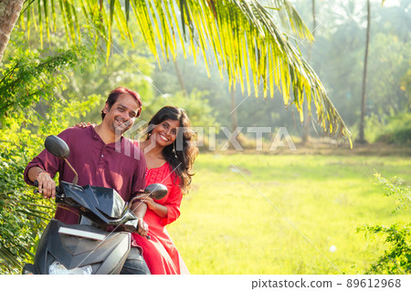 happy indian married couple riding on motorbike adventure in tropical jungle in Goa India copyspace palm trees happy indian married couple riding on motorbike adventure in tropical jungle in Goa India copyspace palm trees 89612968