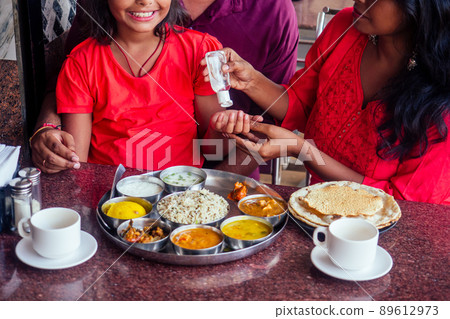 Father ,mother and little girl using wash hand sanitizer gel before eating in india cafe Father ,mother and little girl using wash hand sanitizer gel before eating in india cafe 89612973