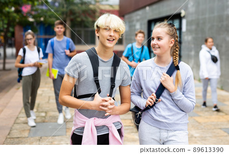 Teen girl going to lessons with classmate on autumn day 89613390