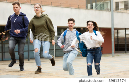 Cheerful teenagers running on city street 89613574