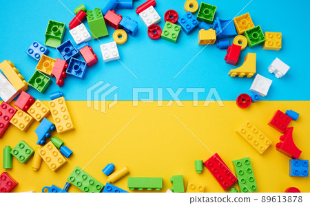 Scattered parts of a plastic children's designer, top view. Yellow blue background Scattered parts of a plastic children's designer, top view. Yellow blue background 89613878