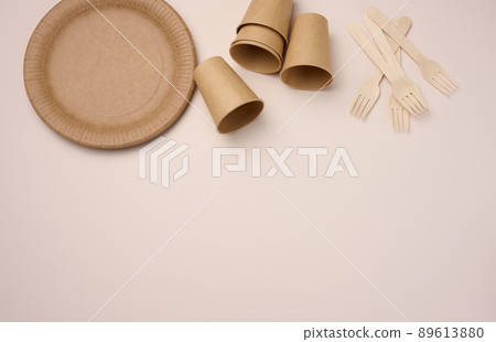 Brown paper cups and plates on a beige background. Recyclable garbage, rejection of plastic, top view Brown paper cups and plates on a beige background. Recyclable garbage, rejection of plastic, top view 89613880