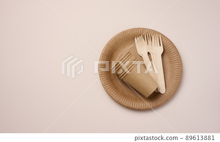 Brown paper cups and plates on a beige background. Recyclable garbage, rejection of plastic Brown paper cups and plates on a beige background. Recyclable garbage, rejection of plastic 89613881