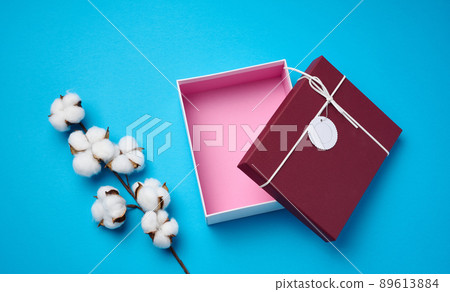 empty open cardboard box for gifts and a twig with cotton flowers on a blue background, top view empty open cardboard box for gifts and a twig with cotton flowers on a blue background, top view 89613884