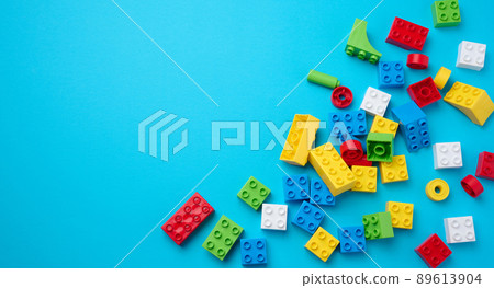 Scattered parts of a plastic children's designer, top view. Yellow blue background 89613904