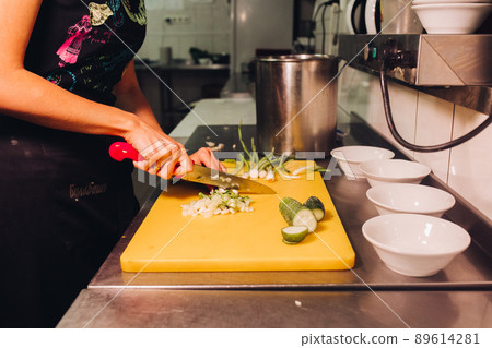 Female holding red knife and cutting fresh onion Female holding red knife and cutting fresh onion 89614281