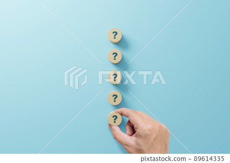 Hand holding wooden block shape with sign question mark symbol on blue background Hand holding wooden block shape with sign question mark symbol on blue background 89614335