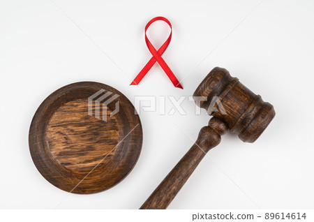 Judicial gavel and red ribbon on a white background. Symbol of the fight against AIDS. 89614614