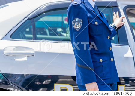 Police officer standing next to a police car 89614700