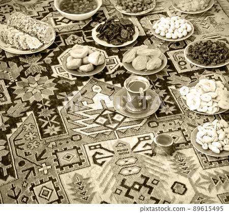 Eastern feast. Asian still life of dried fruits and nuts in plates on a carpet Eastern feast. Asian still life of dried fruits and nuts in plates on a carpet 89615495