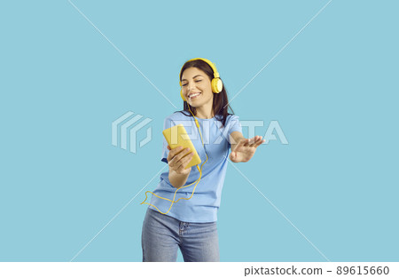 Happy girl in headphones listen to music on smartphone Happy girl in headphones listen to music on smartphone 89615660
