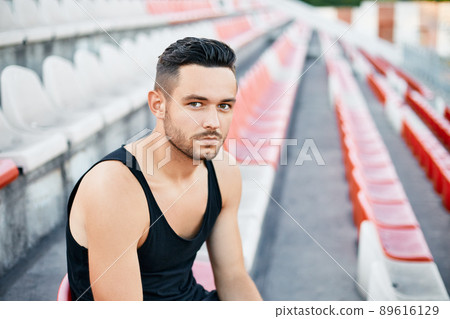 Handsome tired athlete relaxing on stadium stairs after workout Handsome tired athlete relaxing on stadium stairs after workout 89616129