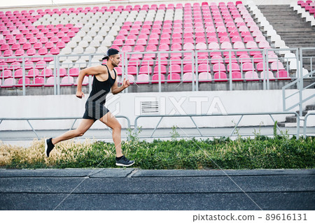 Athlete man running on the running track over empty seats in a sport stadium Athlete man running on the running track over empty seats in a sport stadium 89616131