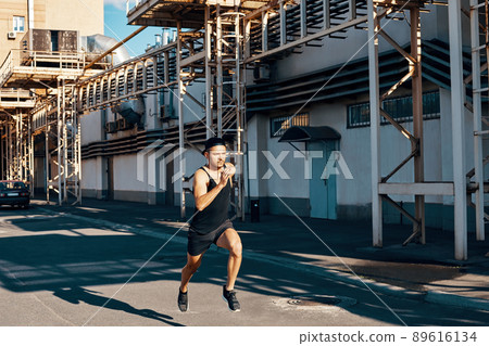 Young man runner running in industrial city background Young man runner running in industrial city background 89616134