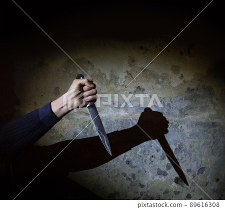 Shadow of the hand holding a big knife Shadow of the hand holding a big knife 89616308
