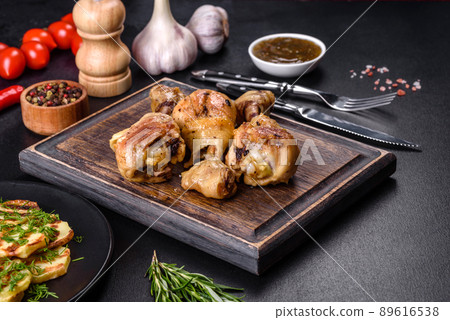 Three chicken legs grilled with spices and herbs on a wooden cutting board 89616538