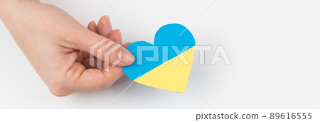 A woman holds a heart with the flag of Ukraine on a white background.  89616555