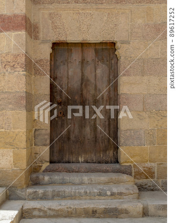 Grunge wooden aged door on exterior stone bricks wall Grunge wooden aged door on exterior stone bricks wall 89617252