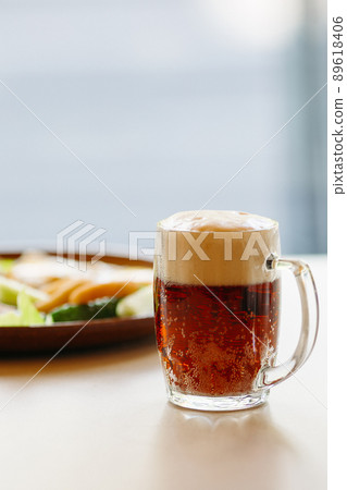 Beer cup standing near appetizers plate. Looking 89618406
