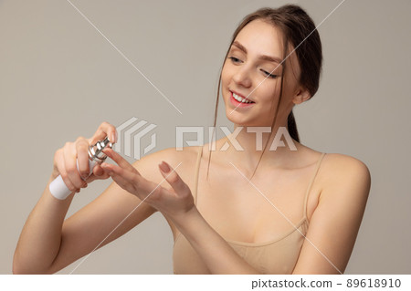 Portrait of tender young girl applying face cream, taking care after skin isolated over grey studio background Portrait of tender young girl applying face cream, taking care after skin isolated over grey studio background 89618910