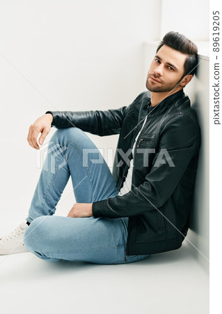 Portrait of handsome thoughtful man sitting on floor leaning to the wall Portrait of handsome thoughtful man sitting on floor leaning to the wall 89619205