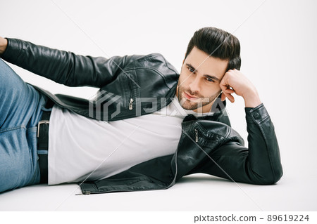 Handsome stylish man posing lying on floor over white studio background. Handsome stylish man posing lying on floor over white studio background. 89619224
