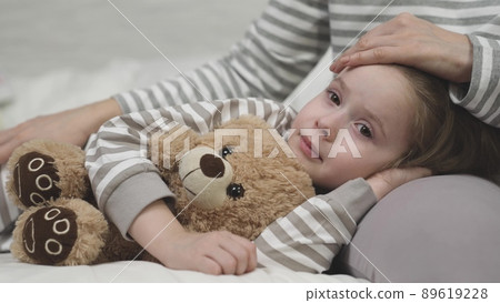 little child daughter lies her mother lap hugging teddy bear. time sleep kid. mom strokes cares girl daughter head. nice relaxation before bed. childhood dream arm mother. happy family life together. little child daughter lies her mother lap hugging teddy bear. time sleep kid. mom strokes cares girl daughter head. nice relaxation before bed. childhood dream arm mother. happy family life together. 89619228