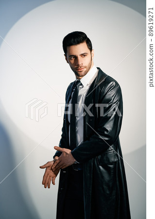 Handsome trendy man posing in the spotlight on studio background Handsome trendy man posing in the spotlight on studio background 89619271