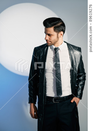 Handsome trendy man posing in the spotlight on studio background Handsome trendy man posing in the spotlight on studio background 89619276
