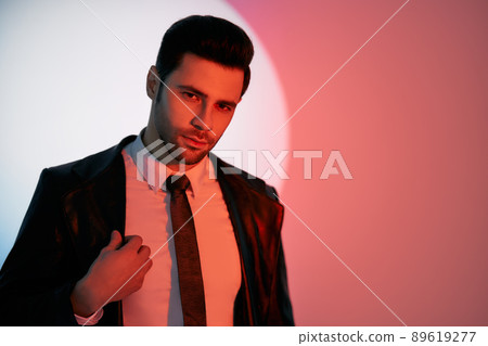 Handsome trendy man posing in the spotlight on studio background Handsome trendy man posing in the spotlight on studio background 89619277