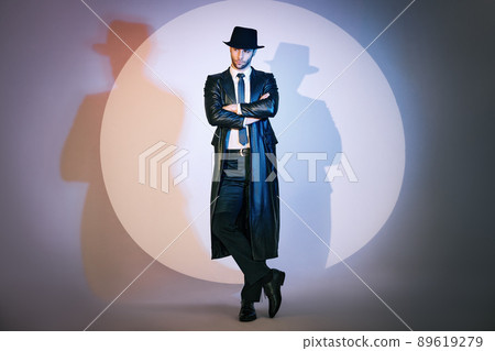 Full length portrait of confident handsome man in black coat and hat with crossed arms posing on studio in the spotlight. Full length portrait of confident handsome man in black coat and hat with crossed arms posing on studio in the spotlight. 89619279