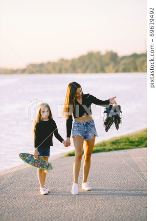Mother and daughter spend time together. Taking time in a park with skateboard. Summer. Mother and daughter spend time together. Taking time in a park with skateboard. Summer. 89619492
