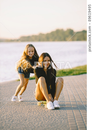 Mother and daughter spend time together. Taking time in a park with skateboard. Summer. Mother and daughter spend time together. Taking time in a park with skateboard. Summer. 89619495