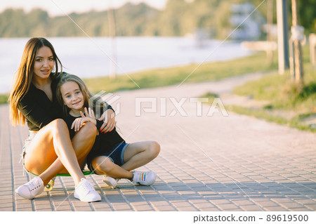 Mother and daughter spend time together. Taking time in a park with skateboard. Summer. Mother and daughter spend time together. Taking time in a park with skateboard. Summer. 89619500