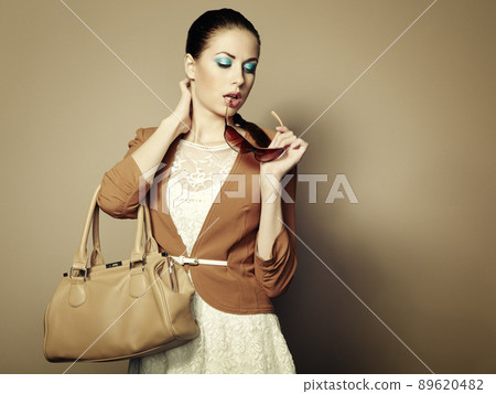 Portrait of beautiful young woman with a leather bag 89620482